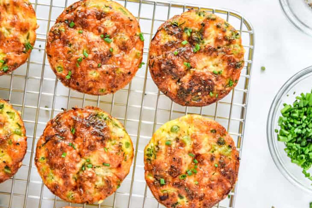 Mini quiches cooling on a wire rack with chives and peas